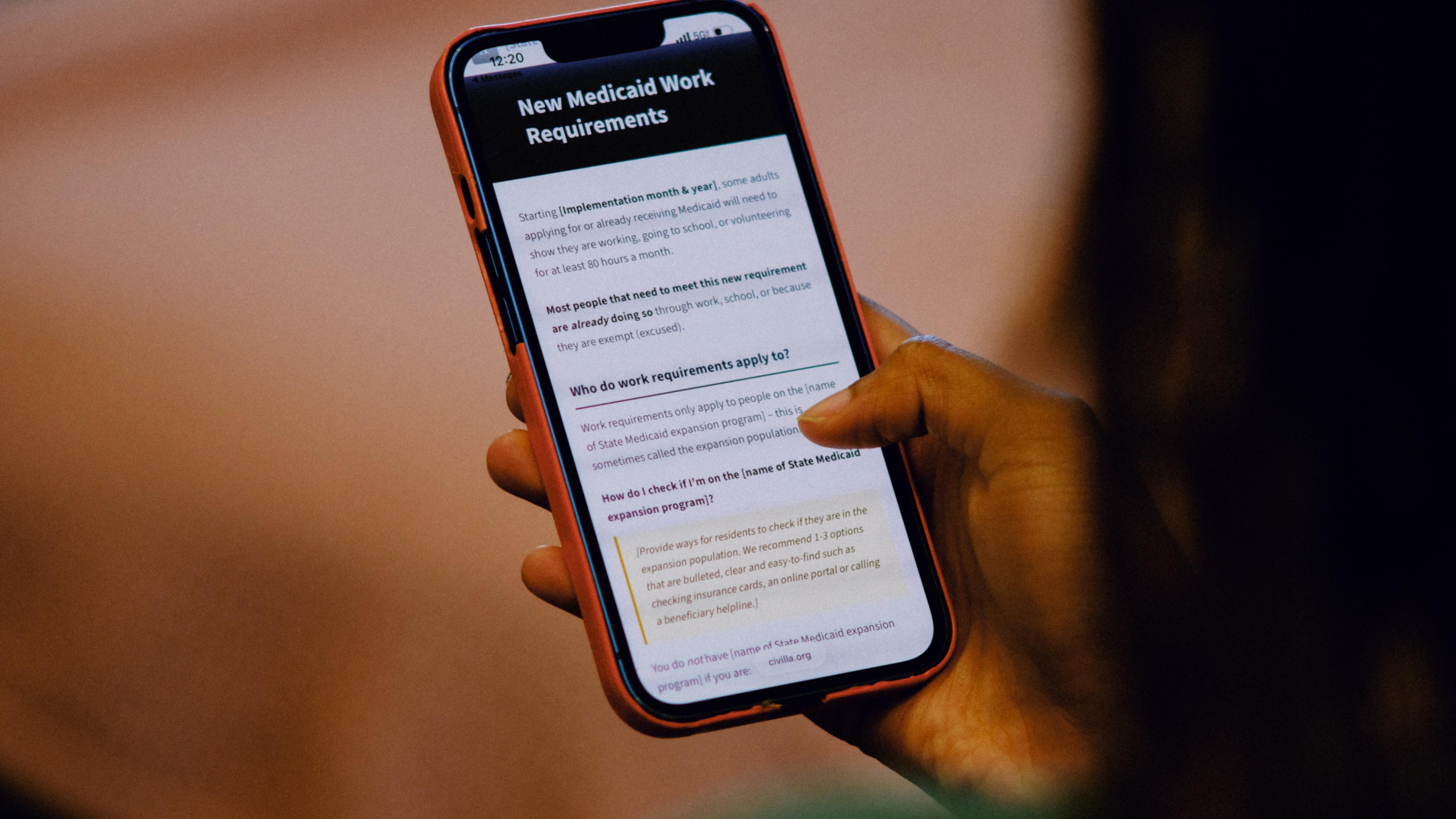A person holding a smartphone with a screen displaying information about new Medicaid work requirements, including questions and details in black and white text.
