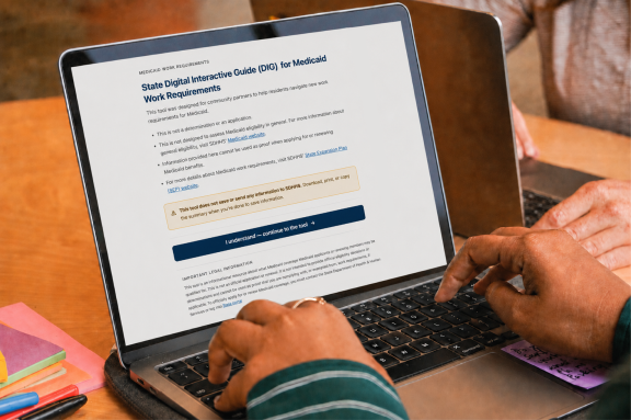 A person typing on a laptop screen displaying the State Digital Interactive Guide (DIG) for Medicaid Work Requirements, a tool to help users understand work requirements, which includes a button to continue and legal information.