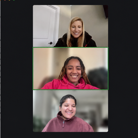 Screenshot of a video call with three people smiling, each in a separate frame, on a virtual meeting platform with a black background.