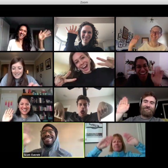 A Zoom video call with twelve people in individual boxes, all smiling and waving at their cameras, appearing cheerful and engaged in a virtual group meeting.